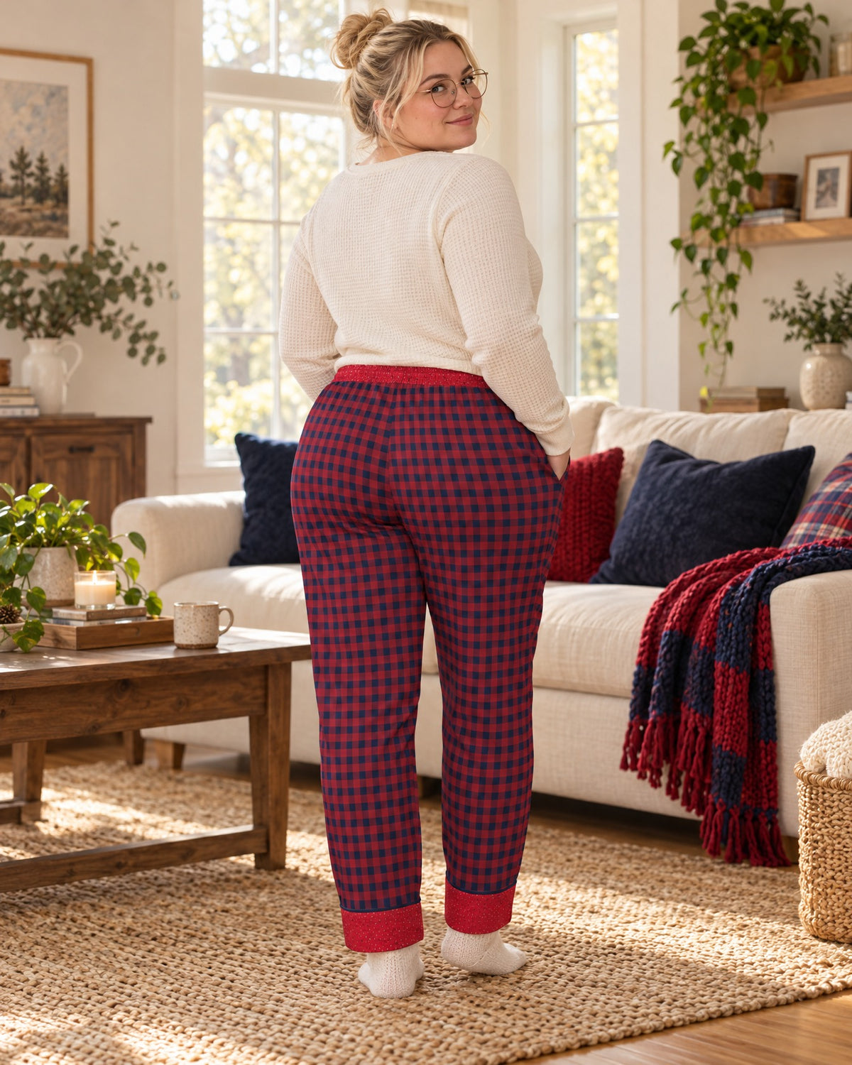 Back view of a woman in the Cherry & Navy satin pajama pants with a cream knit top, plaid waistband and cuffs