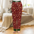 Cranberry-red satin pajama pants printed with iced gingerbread men, candy canes and snowflakes, forest-green cuffs with gold piping