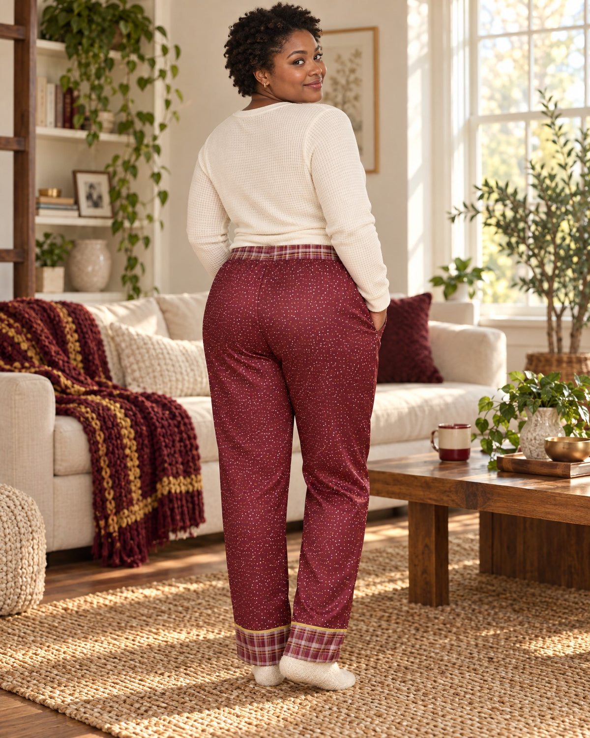 Back view of a woman in the Garnet & Honey satin pajama pants with a cream knit top, plaid waistband and cuffs