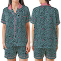 A women's pajama set shown on a model from the front and back, featuring a dark teal-green background with a black cartoon cat pattern and pink accents on the collar, trim, and small details.