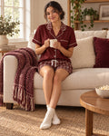 Maroon & Cream satin pajama set worn by a woman sitting on a sofa with a coffee mug, deep maroon top with tiny cream dots