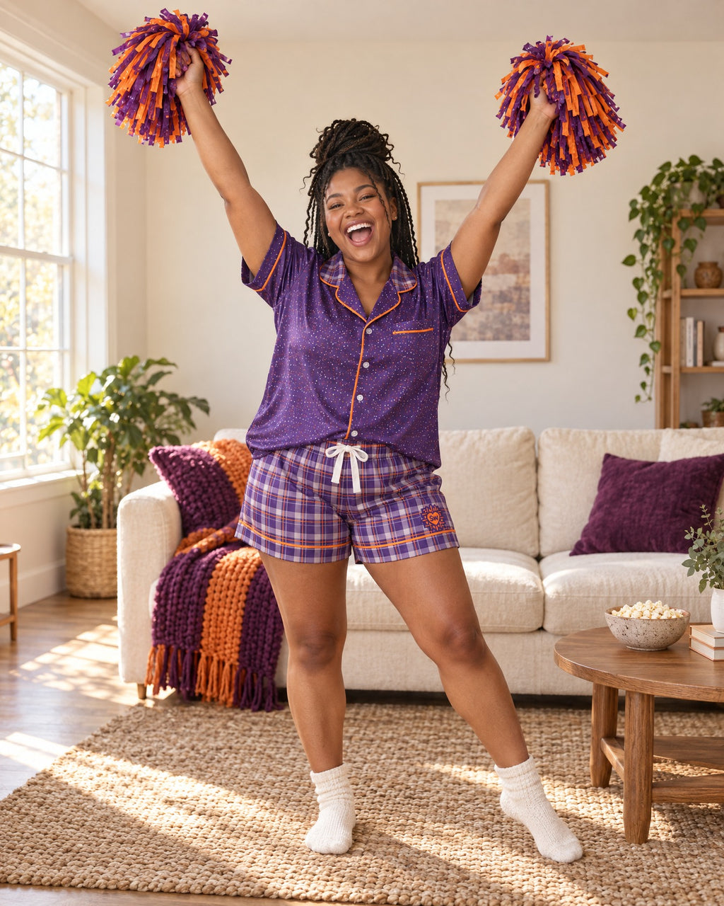 Woman cheering with both arms raised in the Orange & Plum satin pajama set, plain pom-poms