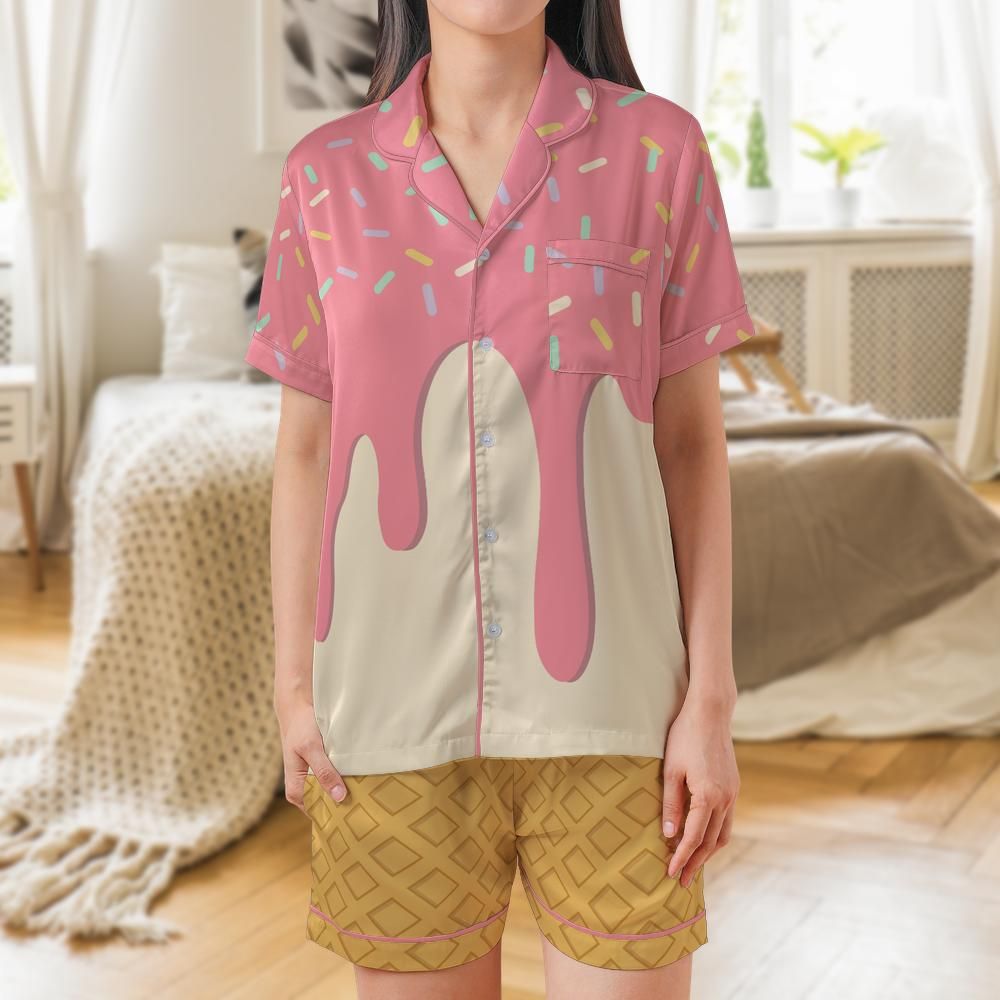 A woman wearing a pink and cream drip-pattern pajama set with yellow patterned shorts, standing in a bright bedroom.