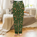 Pine-green satin pajama pants printed with iced gingerbread men, candy canes and snowflakes, tonal green cuffs with red piping
