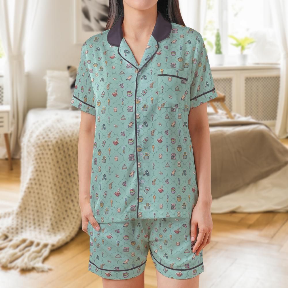 A woman wearing a mint green short-sleeve pajama set with a small multicolor pattern, dark purple collar, and dark trim, standing in a brightly lit bedroom.