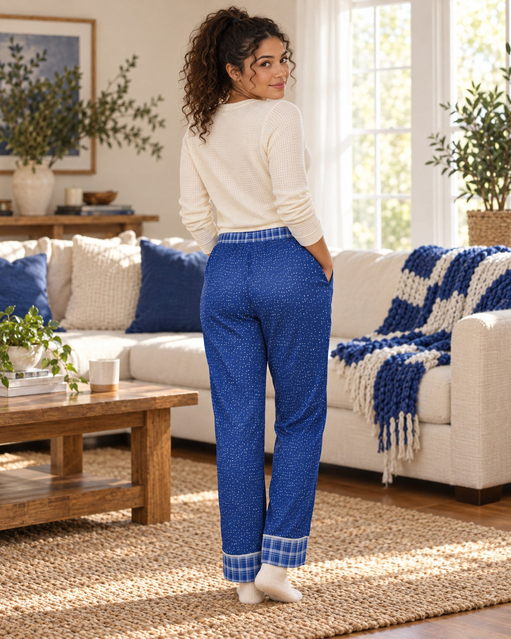 Back view of a woman in the Royal & White satin pajama pants with a cream knit top, plaid waistband and cuffs