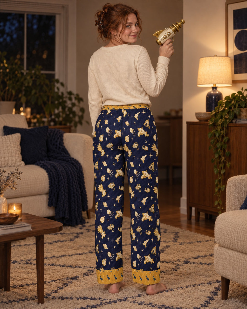Back view of the Space Raygun satin pajama pants: navy satin printed with gold toy rayguns, planets and astronauts, mustard-gold waistband and cuffs
