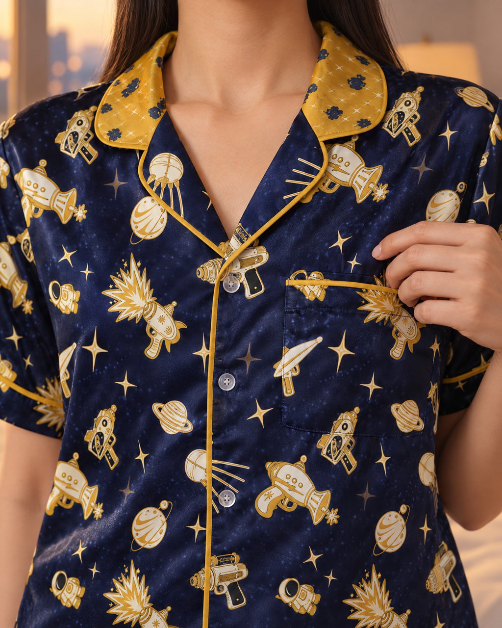 Close-up of the Space Raygun pajama top: mustard-gold collar band, navy lapels printed with gold toy rayguns, chest pocket and gold piping