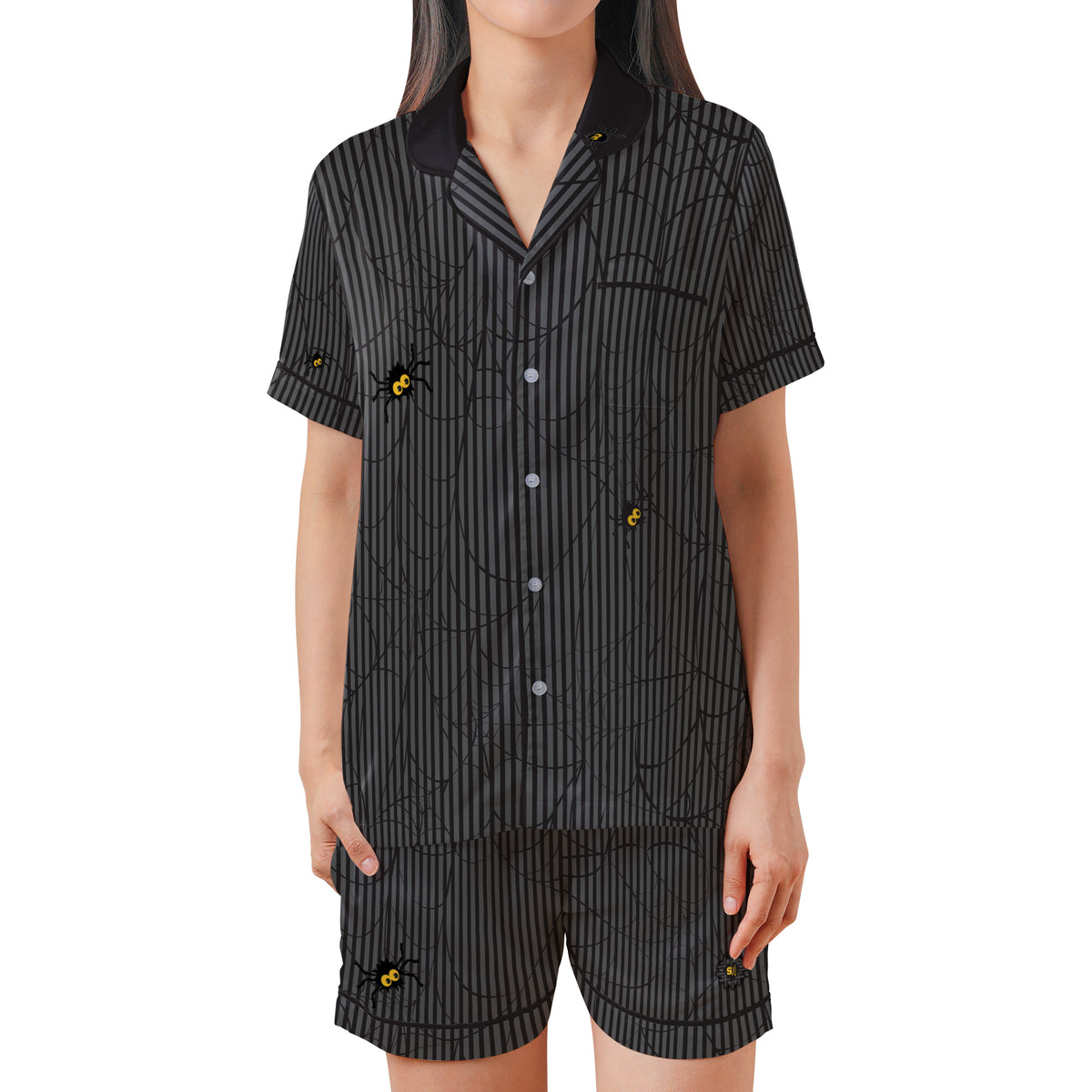 A woman modeling a matching short-sleeve button-front pajama top and shorts set in black with thin gray vertical stripes, spiderweb line patterning, and small embroidered yellow-and-black bees. The background is solid white.